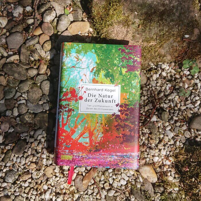 Die Natur der Zukunft. Das SAchbuch von Bernhard Kegel liegt auf Kies und Steinen in einem Garten