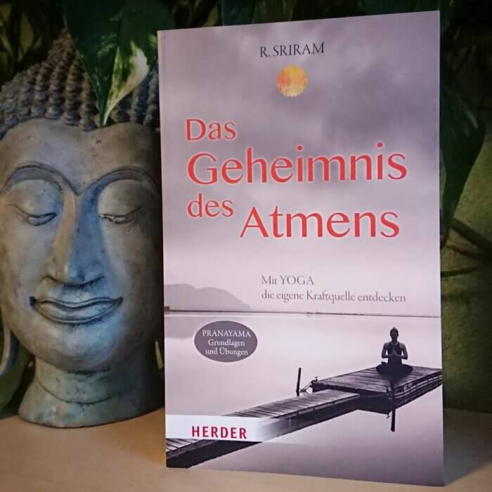 Sriram - Das Geheimnis des Atmens. Taschenbuch neben einem Buddha-Kopf