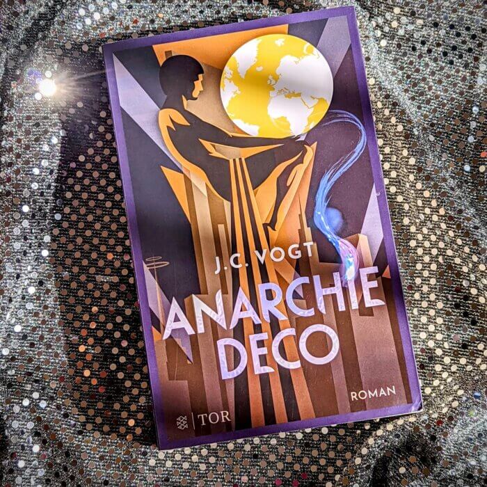 Anarchie Deco. Fantasy-Taschenbuch auf glitzerndem Untergrund.