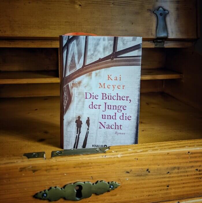 Kai Meyer: Die Bücher, der Junge und die Nacht. Der Roman, der über weite Strecken in Leipzig spielt, wurde aufrecht stehend in einem alten Möbelstück fotografiert.