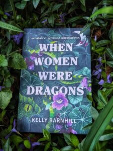 Foto: when women were dragons. Das Buch liegt im blühenden Immergrün, was genau zum Cover passt